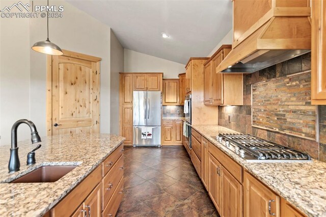 kitchen featuring a large fireplace, stainless steel gas stovetop, an island with sink, hanging light fixtures, and vaulted ceiling