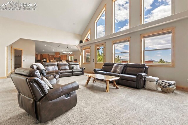 living room with a high ceiling, an inviting chandelier, and light carpet