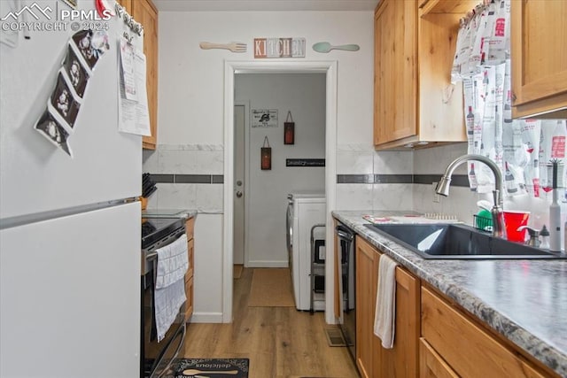 kitchen featuring white fridge, light hardwood / wood-style flooring, independent washer and dryer, black stove, and sink