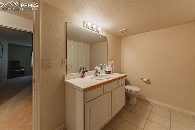 bathroom featuring vanity, a textured ceiling, toilet, and tile patterned flooring