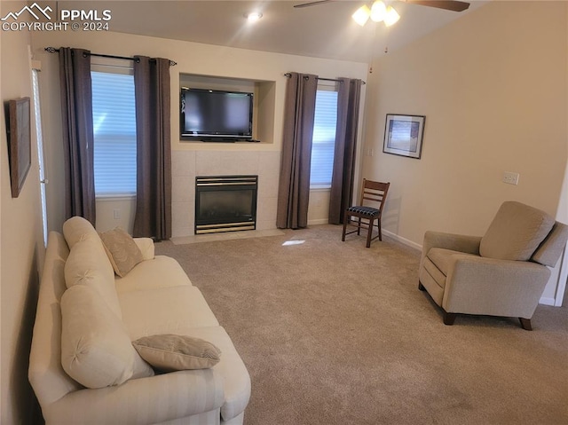 carpeted living room with a tiled fireplace and ceiling fan