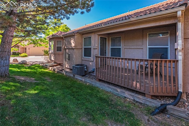 view of side of property featuring cooling unit, a wooden deck, and a lawn