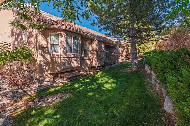 view of side of home with a yard and cooling unit