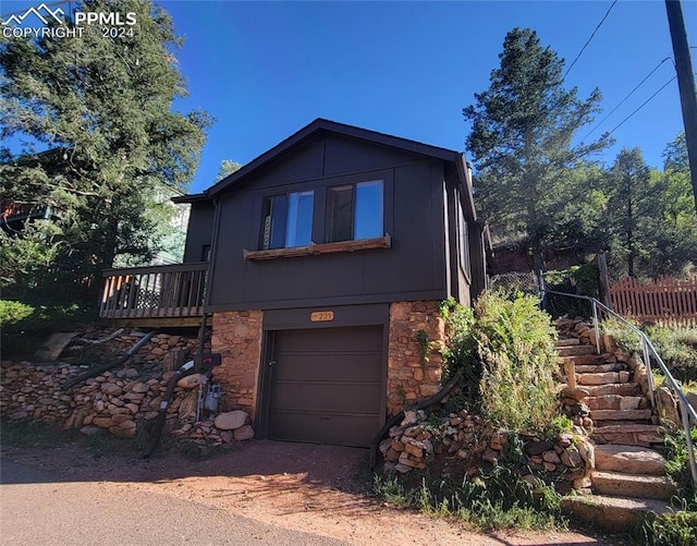 231 Plainview Pl, Manitou Springs, CO 80829 - view of front of property featuring stone siding, an attached garage, fence, and driveway