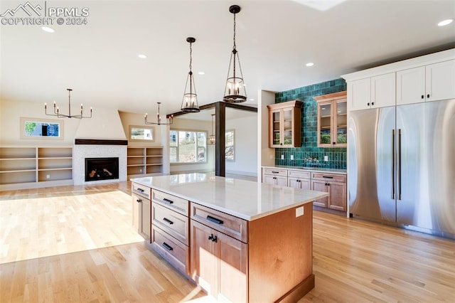 kitchen with stainless steel built in fridge, a center island, light hardwood / wood-style flooring, and decorative light fixtures