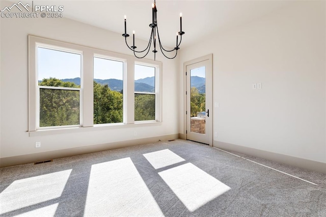 unfurnished dining area with a notable chandelier, a mountain view, and light colored carpet