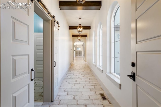 hall featuring beam ceiling and a barn door