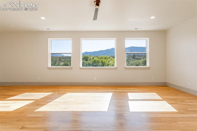 unfurnished room featuring a mountain view and light hardwood / wood-style floors