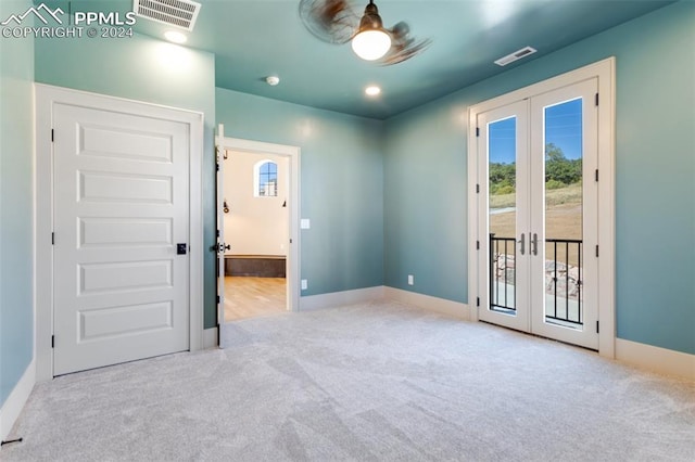 spare room with french doors, light colored carpet, and ceiling fan