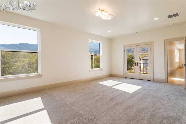 carpeted empty room with french doors and a mountain view