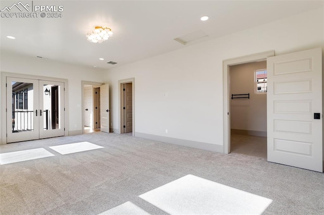 unfurnished bedroom with french doors and light colored carpet