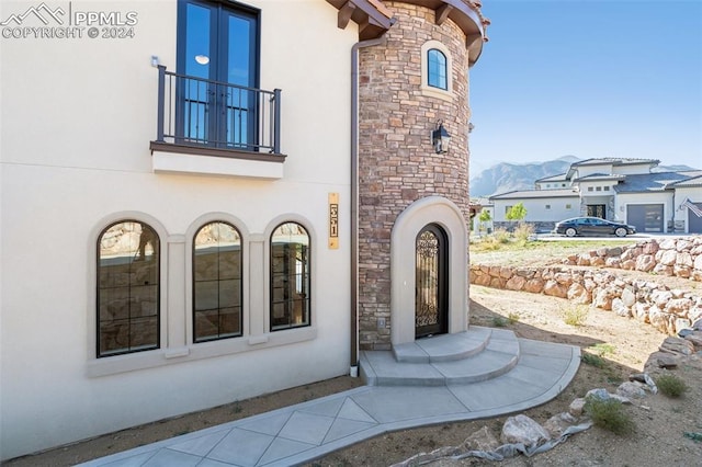 view of exterior entry with a mountain view and a balcony