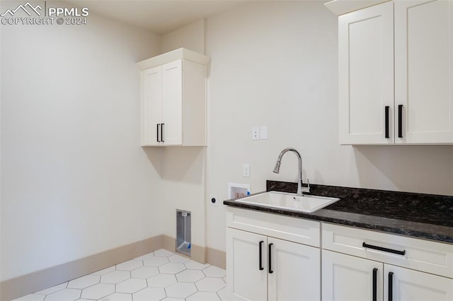 laundry room featuring hookup for a washing machine, light tile patterned flooring, sink, hookup for an electric dryer, and cabinets