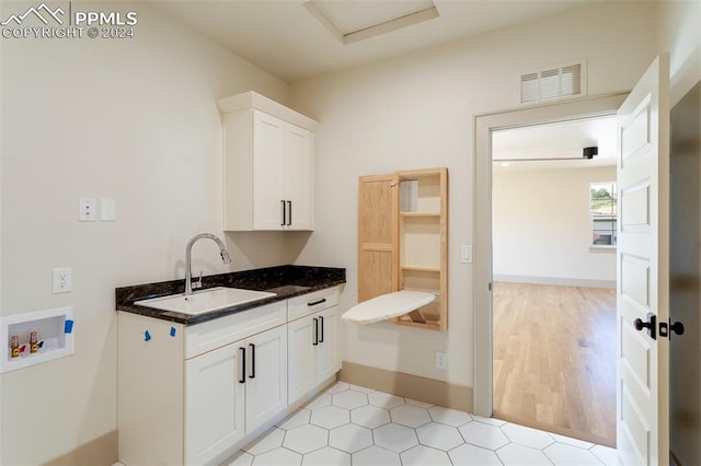 interior space featuring light hardwood / wood-style flooring, white cabinets, sink, and dark stone counters