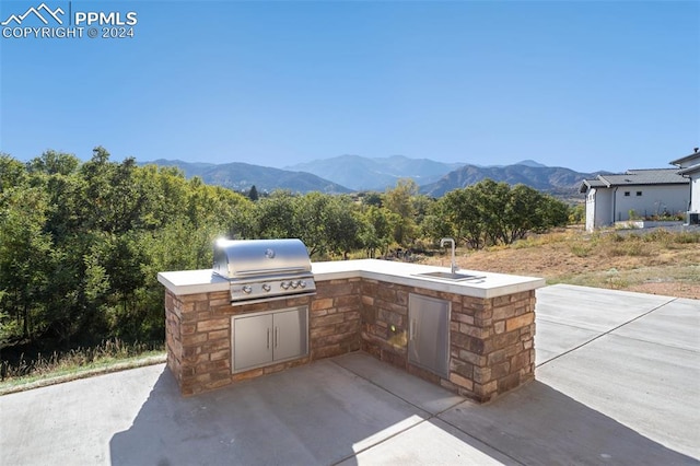 view of patio / terrace featuring an outdoor kitchen, sink, a mountain view, and area for grilling