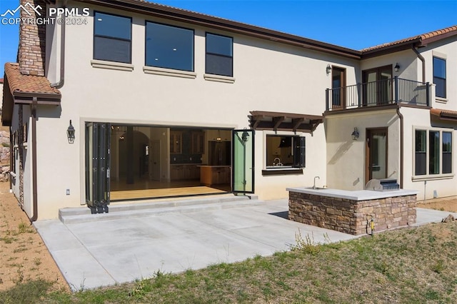 back of house featuring a balcony and a patio