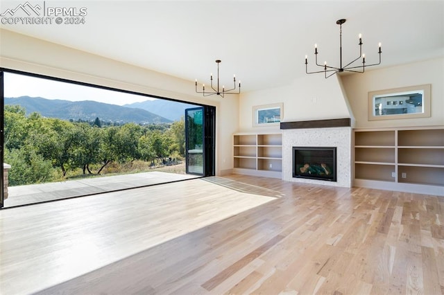 unfurnished living room with a tiled fireplace, a mountain view, and light wood-type flooring