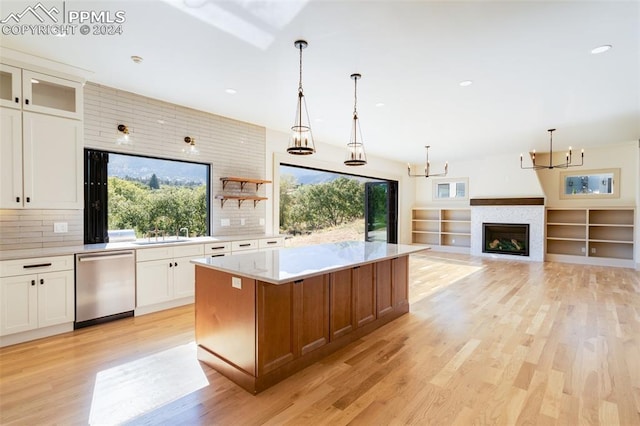 kitchen with tasteful backsplash, a kitchen island, stainless steel dishwasher, white cabinets, and light hardwood / wood-style flooring