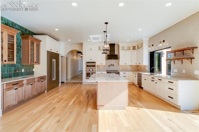 kitchen featuring a kitchen island, decorative light fixtures, premium range hood, white cabinets, and light hardwood / wood-style floors