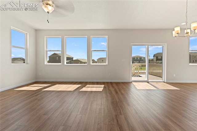 unfurnished living room featuring a healthy amount of sunlight, dark hardwood / wood-style floors, and ceiling fan with notable chandelier