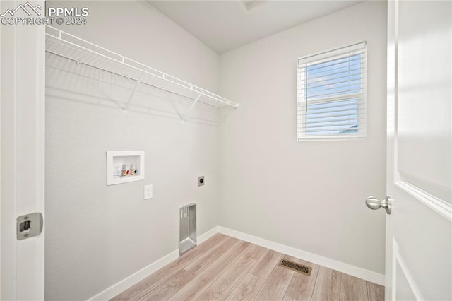 clothes washing area with hookup for a washing machine, hookup for an electric dryer, and light hardwood / wood-style floors