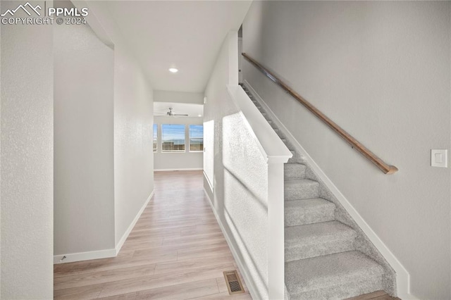 staircase with hardwood / wood-style flooring and ceiling fan