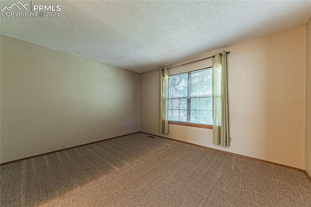 carpeted empty room with a textured ceiling