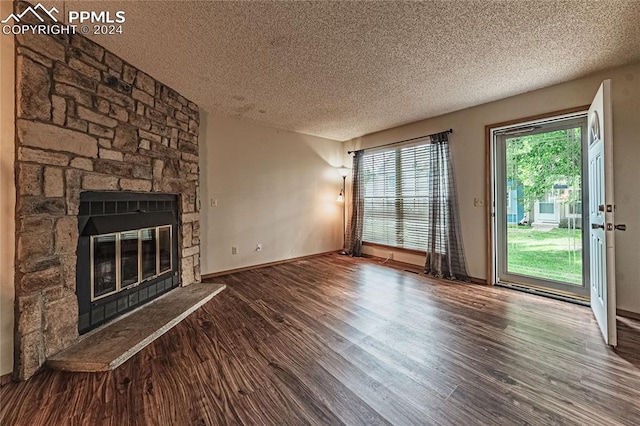 unfurnished living room with a fireplace, a textured ceiling, plenty of natural light, and wood-type flooring