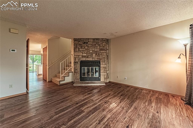 unfurnished living room with a fireplace, dark hardwood / wood-style floors, and a textured ceiling