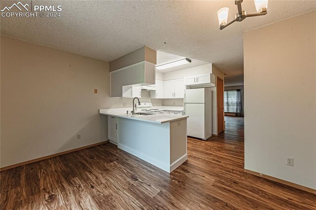 kitchen with a textured ceiling, white fridge, dark hardwood / wood-style floors, kitchen peninsula, and white cabinets