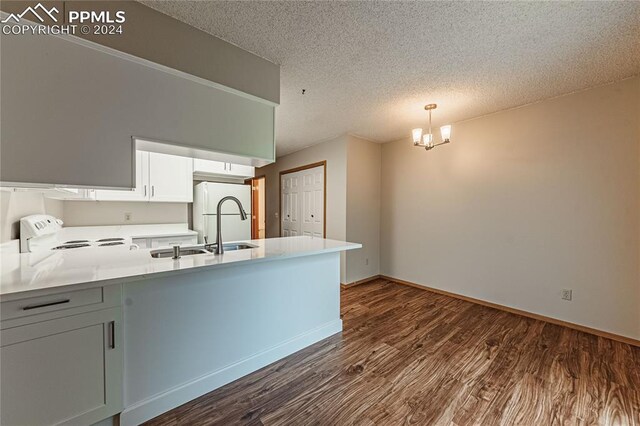 kitchen with hanging light fixtures, white appliances, dark hardwood / wood-style flooring, white cabinetry, and kitchen peninsula