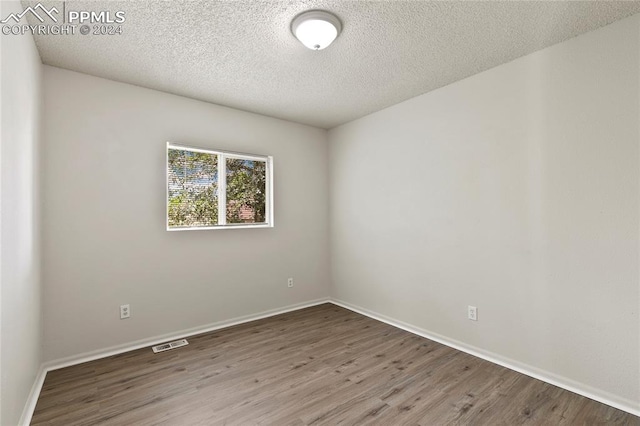 spare room with a textured ceiling and hardwood / wood-style flooring