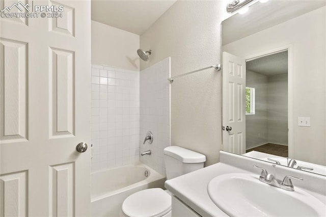 full bathroom featuring tiled shower / bath, vanity, and toilet