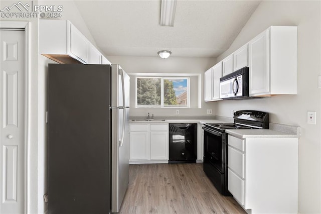 kitchen featuring light wood-type flooring, white cabinetry, black appliances, sink, and lofted ceiling