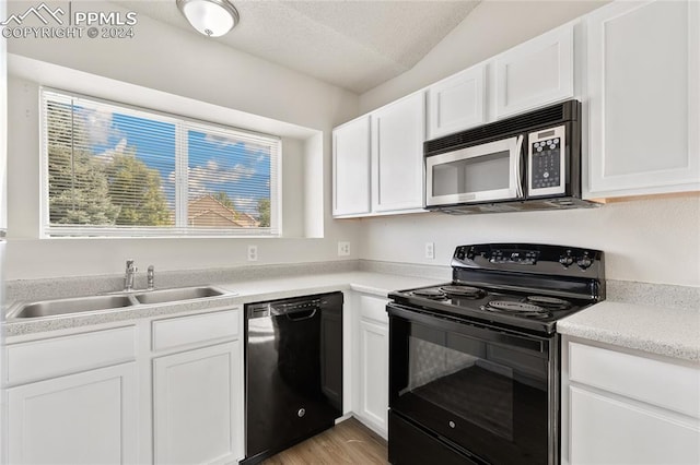 kitchen featuring light hardwood / wood-style floors, white cabinetry, sink, black appliances, and a textured ceiling