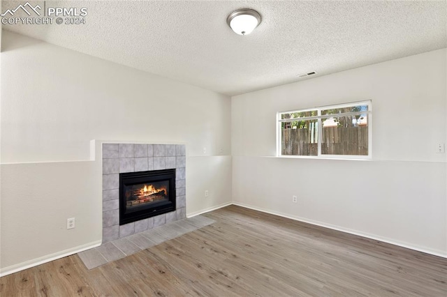 unfurnished living room featuring a textured ceiling, hardwood / wood-style floors, and a fireplace