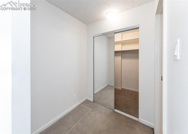 unfurnished bedroom with a closet, carpet flooring, and a textured ceiling