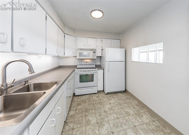 kitchen with white appliances, sink, white cabinets, and a textured ceiling