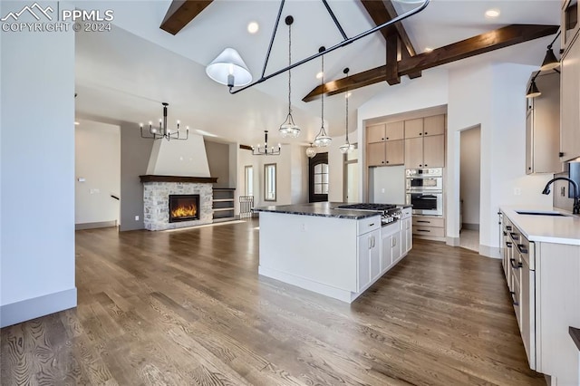 kitchen with a stone fireplace, sink, dark hardwood / wood-style floors, decorative light fixtures, and a kitchen island