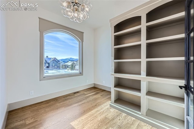 spare room with a notable chandelier and light wood-type flooring