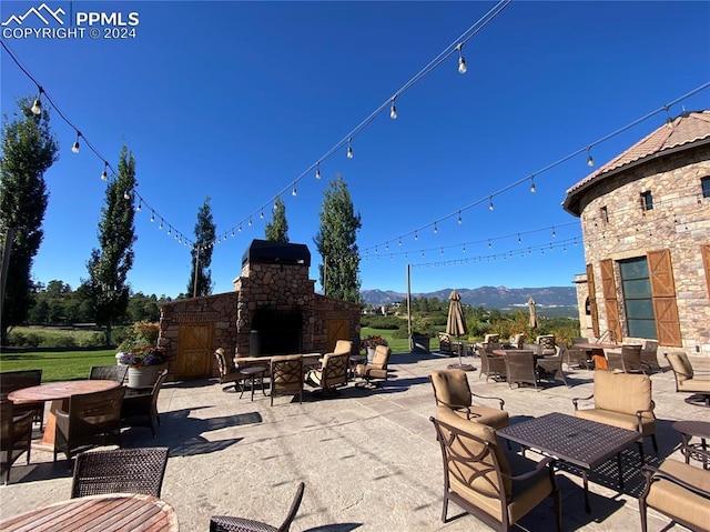 view of patio with a mountain view and an outdoor stone fireplace