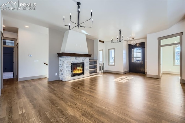 unfurnished living room with a fireplace, an inviting chandelier, and hardwood / wood-style flooring