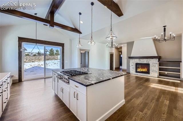 kitchen with white cabinets, vaulted ceiling with beams, dark hardwood / wood-style floors, a fireplace, and decorative light fixtures