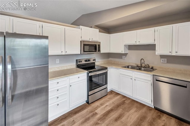 kitchen with white cabinetry, appliances with stainless steel finishes, sink, light hardwood / wood-style floors, and lofted ceiling