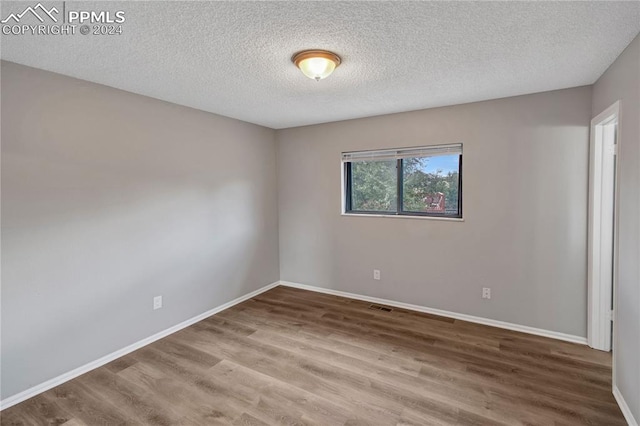 spare room featuring a textured ceiling and hardwood / wood-style flooring