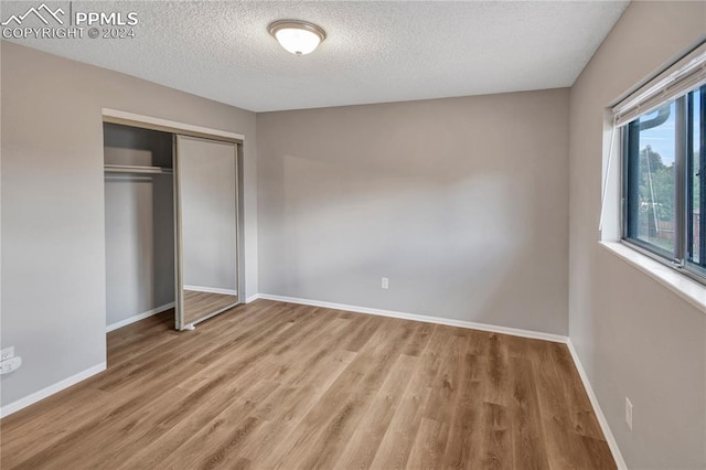 unfurnished bedroom featuring a textured ceiling, hardwood / wood-style flooring, and a closet