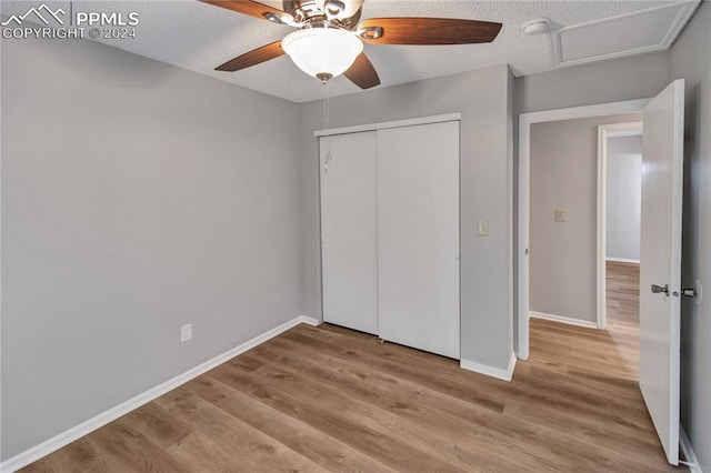 unfurnished bedroom featuring ceiling fan, a textured ceiling, a closet, and light hardwood / wood-style flooring