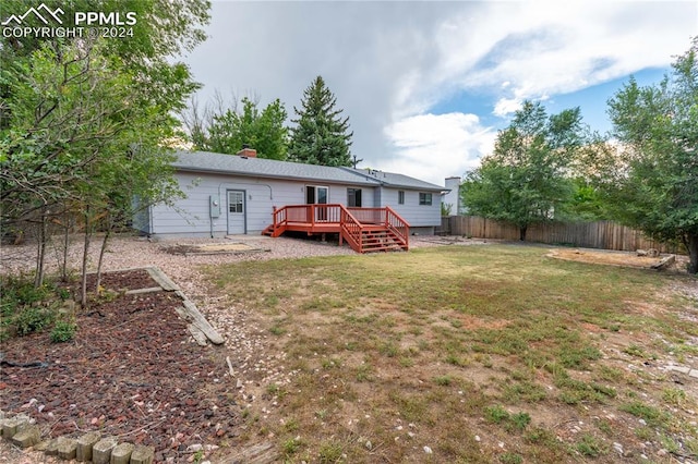 back of property featuring a lawn and a wooden deck