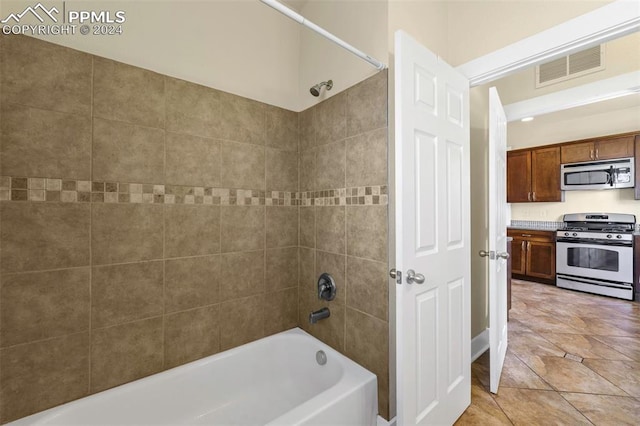 bathroom with tiled shower / bath combo and tile patterned floors