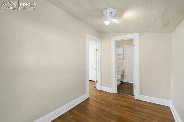 spare room with dark hardwood / wood-style floors and a textured ceiling